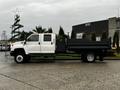 A white 2005 GMC C5 Duramax truck with a flatbed and dual rear wheels parked on a concrete surface