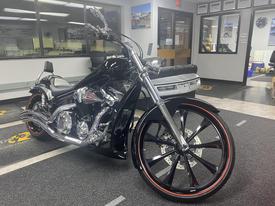 A black 2017 Honda VT1300CXA motorcycle with chrome accents and large black and red wheels positioned in an indoor setting