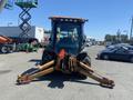 A 2008 Case Super 580M backhoe loader facing forward with a black cabin a large front bucket and stabilizer arms extended