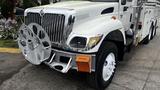 A white 2006 International 7500 truck with a shiny chrome grille and a large circular winch mounted on the front bumper