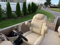 A beige captain's chair with armrests is positioned at the helm of a boat with various controls and dashboard instruments visible nearby