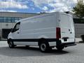 A white 2020 Mercedes-Benz Sprinter van is parked, featuring a smooth rear panel and black trim along the bottom multicolored highlights on the sides and tall wheels