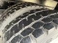 Two close-up truck tires with rugged tread patterns on a vehicle's undercarriage