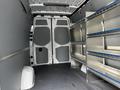 Interior view of a 2023 Mercedes-Benz Sprinter cargo van showing open double rear doors and metal shelving units on one side