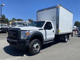 A white 2015 Ford F-450 SD box truck with a rectangular cargo area and multiple visible marker lights on the roof