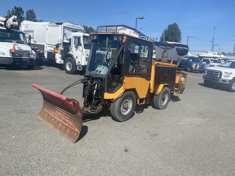 A 2010 Trackless MT6 utility vehicle with a front-mounted snowplow attachment in a parking lot