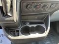 Interior console of a 2016 Ford Transit featuring climate control knobs a power outlet and cup holders