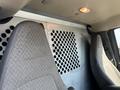 Interior view of a 2016 GMC Savana featuring two front seats and a partition with circular ventilation holes