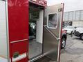 A red 2007 Ford F-550 ambulance with an open rear door showing the interior seating and metal flooring