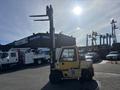 A yellow 1993 Hyster H80XL forklift with two long forks extended mounted on a wheeled chassis