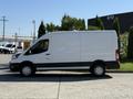 A 2022 Ford Transit van in white with a high roof and sliding side door, parked with its side profile visible