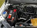The engine compartment of a 2016 Ford F-150 featuring a black engine block battery and various automotive components