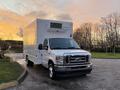 A white 2021 Ford Econoline truck with a large cargo box and an air conditioning unit mounted on top