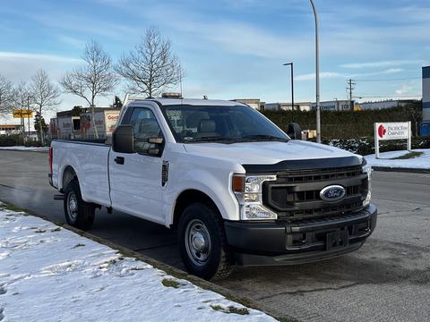 A white 2021 Ford F-250 SD truck with a single cab and open bed parked on a snowy street