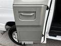 A silver-gray door of a 2014 Ford Econoline with a handle and a textured panel design