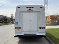 A white 2010 Ford Econoline van with a rear door labeled as an emergency exit and a wheelchair symbol above the door