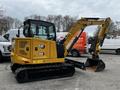 A yellow 2024 Caterpillar 306 compact excavator with a front bucket and a rear digging arm is positioned on tracks