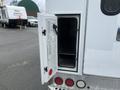 A side view of a 2016 Chevrolet Express with an open service door revealing storage space inside