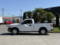 A white 2014 Ford F-150 pickup truck with a single cab and chrome wheels parked next to palm trees