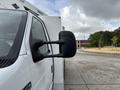 A 2017 Ford Econoline van with a close-up view of its driver's side mirror