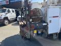 A 2007 International 7300 truck with a mounted hydraulic lift and various equipment attached to the rear showing signs of wear and rust