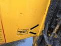 A close-up of a yellow Bandit 200+ wood chipper with a label that reads "GREASE DAILY" and arrows indicating where to apply grease