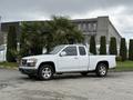 A white 2012 GMC Canyon pickup truck with chrome wheels parked in front of palm trees and shrubs