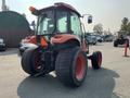 A red 2014 Kubota tractor with a cab and large rear tires facing away from the viewer