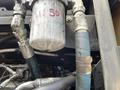 A close-up of a John Deere 350 engine showing a fuel filter with visible markings and metal and rubber hoses connected to it