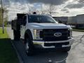 A 2018 Ford F-550 pickup truck with a white exterior and a black bed parked on the side of the road