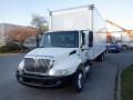 A white 2014 International Durastar box truck with a large cargo area and a black grille parked with the driver's side facing forward