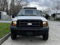 A white 2007 Ford F-550 truck with a black front grille and multiple orange lights on the roof facing straight ahead