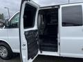 A 2012 Chevrolet Express van with an open side door revealing a spacious interior and black flooring