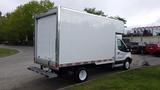 A 2018 Ford Transit with a large white cargo van body parked with its rear facing the viewer