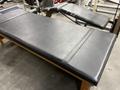 A black padded gym bench with a wooden frame designed for strength training and exercise workouts