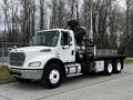 A 2006 Freightliner M2 112 truck with a white body and a flatbed cargo area featuring a hydraulic crane mounted on the rear