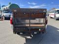 A 2013 Ford F-250 SD with a rusted flatbed and mesh sides is parked showing the back view and taillights