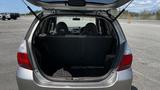 A 2006 Honda Fit with its rear hatch open revealing the spacious cargo area and two rear seats folded down