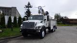 A 2012 International 7400 truck with a utility body and equipment mounted on top standing on a paved path