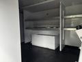 A white 2017 Ford Econoline van interior with empty shelves and a bench-like structure on the floor