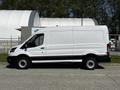 A white 2022 Ford Transit van with a black stripe along the bottom is parked on a concrete surface facing left