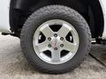 A close-up of a silver alloy wheel with a GMC logo on a tire labeled MILDPEAK AT with visible tread patterns