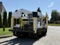 A 2014 Achiever DPM52MH is a tracked vehicle featuring a white and yellow exterior with various equipment attached including a crane arm and a large platform at the back