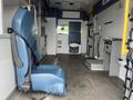 A blue driver's seat in the foreground of an empty interior of a 2016 Chevrolet Express designed for transport