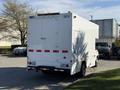 A 2012 Ford Econoline E-450 vehicle in white with red and black stripes and a boxy cargo area at the rear
