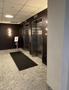 Interior view of an elevator lobby featuring two elevator doors a black mat and a sign on a stand
