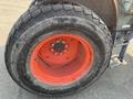 Close-up of a rear tire and wheel of a 2014 Kubota M7060 tractor featuring a rugged tread pattern and an orange rim
