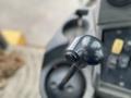 Close-up of the control joystick of a 2012 John Deere 310SJ with a smooth black surface and a slender lever extending vertically