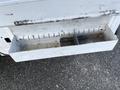 A silver metal storage compartment with a long rectangular shape attached to a vehicle's side featuring a divided section inside