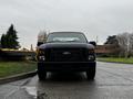 A black 2008 Ford F-250 Super Duty truck facing forward with its headlights visible and a sturdy front grille